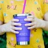 child holding smoothie cup and drinking a smoothie