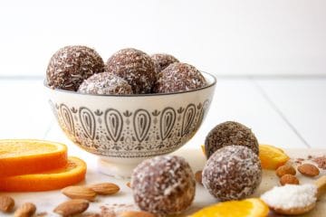 picture of a bowl of chocolate orange almond bliss balls styled with the ingredients placed around the outside.