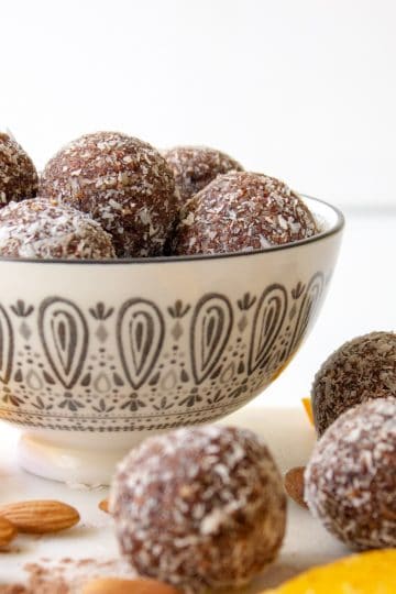 picture of a bowl of chocolate orange almond bliss balls styled with the ingredients placed around the outside.