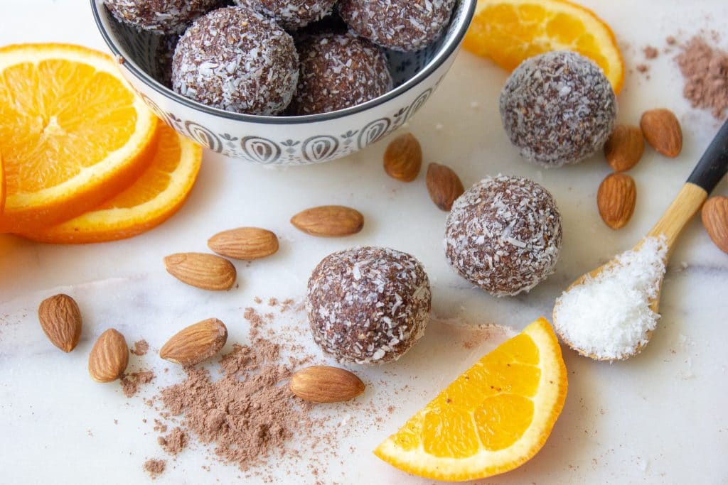 close up picture of chocolate orange almond bliss balls and the ingredients used to make them.