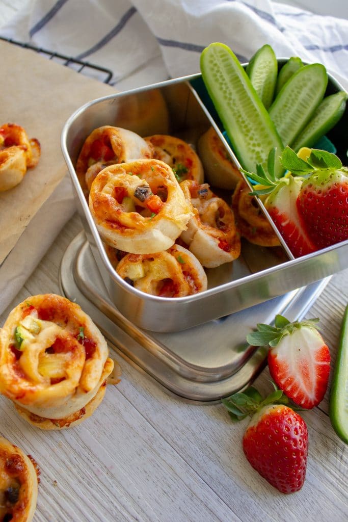 picture of pizza scrolls in a lunchbox with strawberries and cucumber